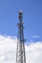 Cell tower against blue sky with clouds. Wireless communication. Royalty Free Stock Photo