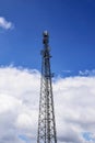 Cell tower against blue sky with clouds. A cell site or tower with antennae and telecommunications equipment is part of cellular