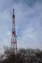 A cell tower on a background of cloudy sky and snow-covered tree branches Royalty Free Stock Photo