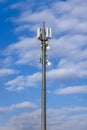 Cell tower with various antennas and signal amplifiers against a blue sky with clouds Royalty Free Stock Photo