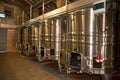Cellar with modern metal tanks in winery wine barrels rows