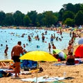 Women, men and children have fun and relax on the sandy beach by the lake on a family outing