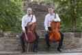 Cellist musician group perform music in the street, close up man playing violin