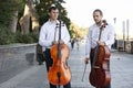 Cellist musician group perform music in the street, close up man playing violin