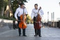 Cellist musician group perform music in the street, close up man playing violin