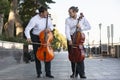 Cellist musician group perform music in the street, close up man playing violin