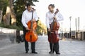 Cellist musician group perform music in the street, close up man playing violin