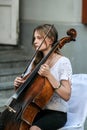 Cellist woman playing on the street, side view.