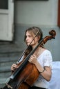 Cellist woman playing on the street, side view.