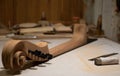 Cello neck and headstock with ebony tuning pegs stays on the workbench in workshop