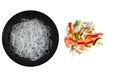 Cellophane or glass noodles in black matte plate and colorful chopped fresh vegetables mix isolated on a white background, top Royalty Free Stock Photo