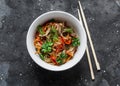 Cellophane noodles with beef, sweet pepper, carrot, onion stir fry on a dark background, top view