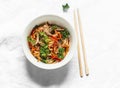 Cellophane noodles with beef, sweet pepper, carrot, onion stir fry on a light background, top view