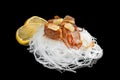 The cellophane with a piece of roasted salmon with tomatoes, onion and parsley isolated on black background