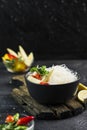 Cellophane rice noodles with vegetables in a black bowl with chopsticks on dark background, side view closeup Royalty Free Stock Photo