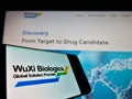 Cellphone with business logo of biotechnology company WuXi Biologics (Cayman) Inc. on screen in front of website.