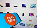 Cellphone with business logo of Dutch e-commerce company Coolblue B.V. on screen in front of website.