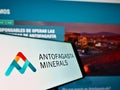 Cellphone with business logo of mining company Antofagasta Minerals S.A. on screen in front of webpage.
