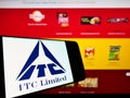 Cellphone with company logo of Indian conglomerate ITC Limited on screen in front of business website.