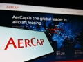 Cellphone with logo of aircraft leasing company AerCap Holdings NV on screen in front of business website.