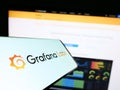 Cellphone with logo of American analytics software company Grafana Labs on screen in front of business website.