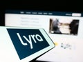 Cellphone with logo of American mental health company Lyra Health Inc. on screen in front of business website.