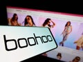 Cellphone with logo of British fashion company Boohoo Group plc on screen in front of business website. Royalty Free Stock Photo