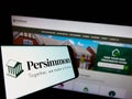 Cellphone with logo of British housebuilding company Persimmon plc on screen in front of business website.