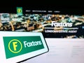 Cellphone with logo of British real estate agency Foxtons Group plc on screen in front of business website.