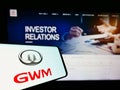 Cellphone with logo of car manufacturer Great Wall Motors Co. Ltd. (GWM) on screen in front of business website.
