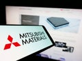 Cellphone with logo of company Mitsubishi Materials Corporation (MMC) on screen in front of website. Royalty Free Stock Photo