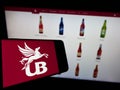 Cellphone with logo of company United Breweries Holdings Limited (UBHL) on screen in front of website.