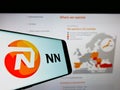 Cellphone with logo of Dutch insurance company NN Group N.V. on screen in front of business website.