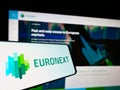 Cellphone with logo of financial services company Euronext N.V. on screen in front of business website.