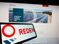 Cellphone with logo of French photovoltaic company Reden Solar S.A.S. on screen in front of business website.