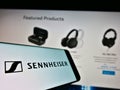 Cellphone with logo of German audio company Sennheiser electronic GmbH Co. KG on screen in front of web page.