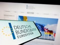 Cellphone with logo of German central bank Deutsche Bundesbank on screen in front of website.