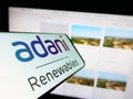 Cellphone with logo of Indian company Adani Green Energy Limited on screen in front of business website.