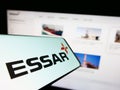 Cellphone with logo of Indian conglomerate Essar Group on screen in front of business website.