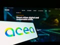 Cellphone with logo of Italian utility company Acea S.p.A. on screen in front of business website.