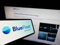 Cellphone with logo of Spanish renewables company BlueFloat Energy LLC on screen in front of website.