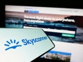 Cellphone with logo of travel metasearch company Skyscanner Ltd. on screen in front of business website.