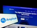 Cellphone with logo of US analytics software company Amplitude Inc. on screen in front of business website.