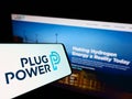 Cellphone with logo of US hydrogen fuel cell company Plug Power Inc. on screen in front of website.