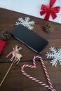 Cellphone, pinecone, reindeer, snowflakes and two candy cane forming a heart on the table Royalty Free Stock Photo