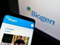 Cellphone with web page of American biotechnology company Biogen Inc. on screen in front of business logo.