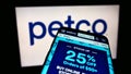 Cellphone with webpage of US retailer Petco Health and Wellness Company Inc. on screen in front of company logo.