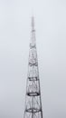 A cellular communications tower, with many antennas, in dense fog, goes into the sky overcast, against the background of an Royalty Free Stock Photo