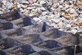 Cellular confinement system - plastic black honeycomb frame filled with small natural stones closeup. Used in construction for Royalty Free Stock Photo