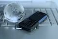 Cellular and glass globe on laptop keyboard Royalty Free Stock Photo